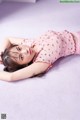 A young woman laying on a bed in a pink dress.