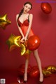 A woman in a red lingerie holding a bunch of balloons.