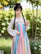 A young girl wearing a colorful dress standing in a garden.