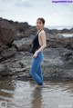 A woman standing in the water near some rocks.