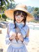 A woman in a straw hat standing on a beach.