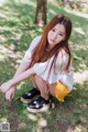 A young woman sitting on the ground in a park.