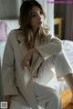 A woman in a white suit sitting on a bed.