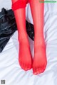 A woman in red stockings is laying on a bed.