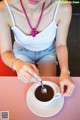 A woman sitting at a table with a cup of coffee.