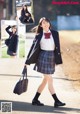 A woman in a school uniform is walking down the street.