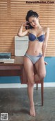 A woman in a blue bra and panties sitting on a chair.