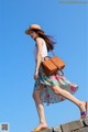 A woman in a hat is walking on a stone wall.