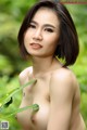 A naked asian woman holding a green leaf in her hand.