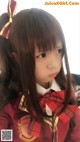 A little girl with long brown hair wearing a red and gold outfit.