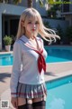 A woman in a school uniform posing by a pool.