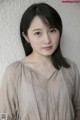 A woman with long black hair standing in front of a wall.