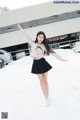 A woman in a school uniform is standing in the snow.