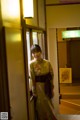 A woman in a kimono standing in a hallway.