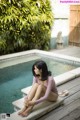 A woman sitting on the edge of a swimming pool.